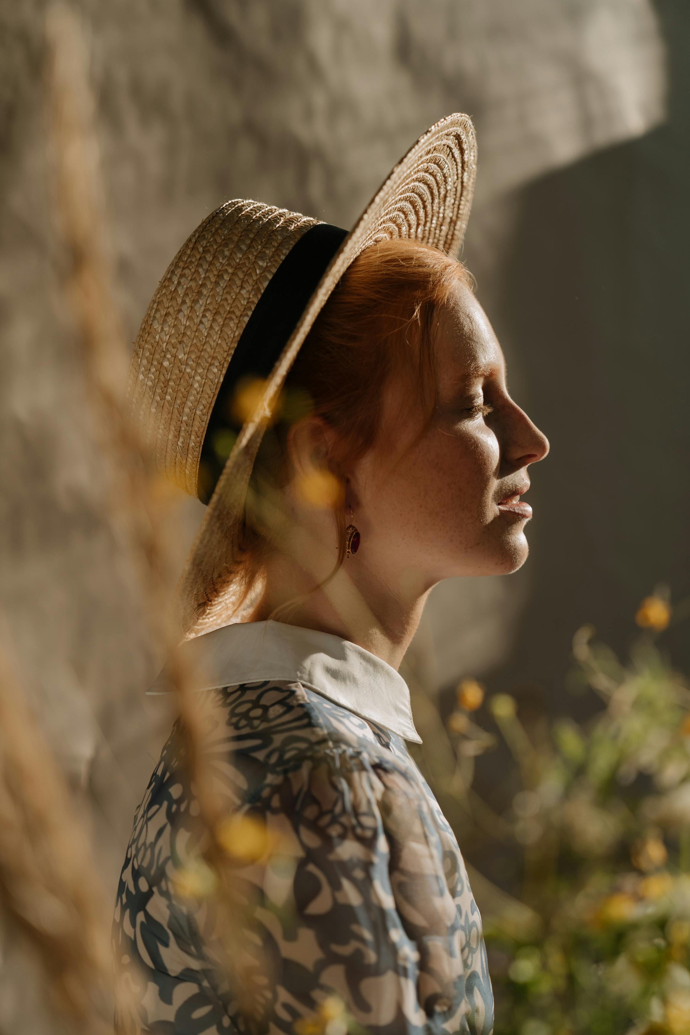 夏日阳光下，一位戴着草帽的红发女子侧影优雅，散发着复古风格