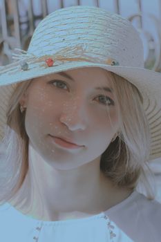 Close-up portrait of a woman wearing a straw hat in soft natural light, emphasizing delicate features.
