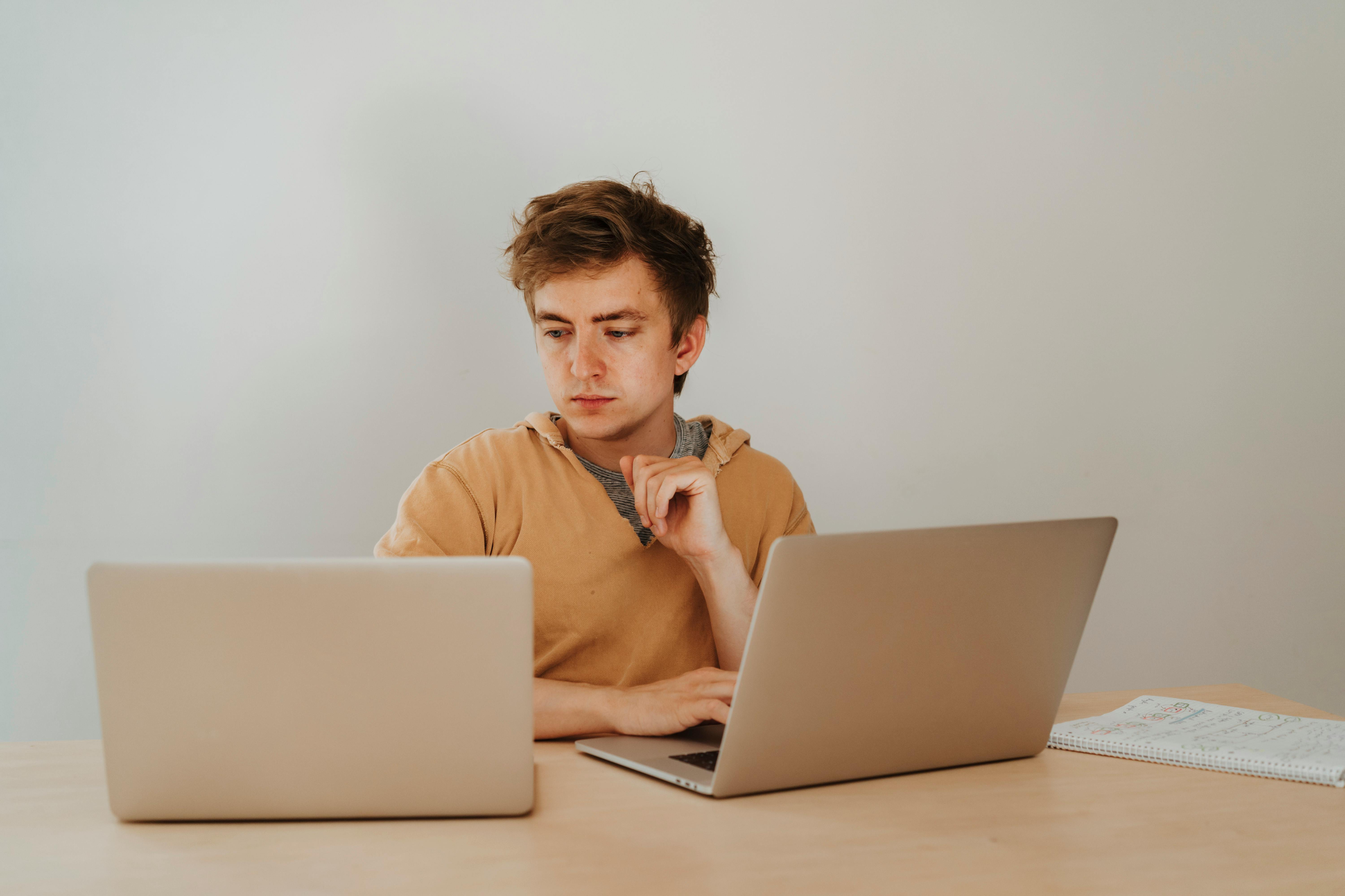 Worried man looking at two laptops