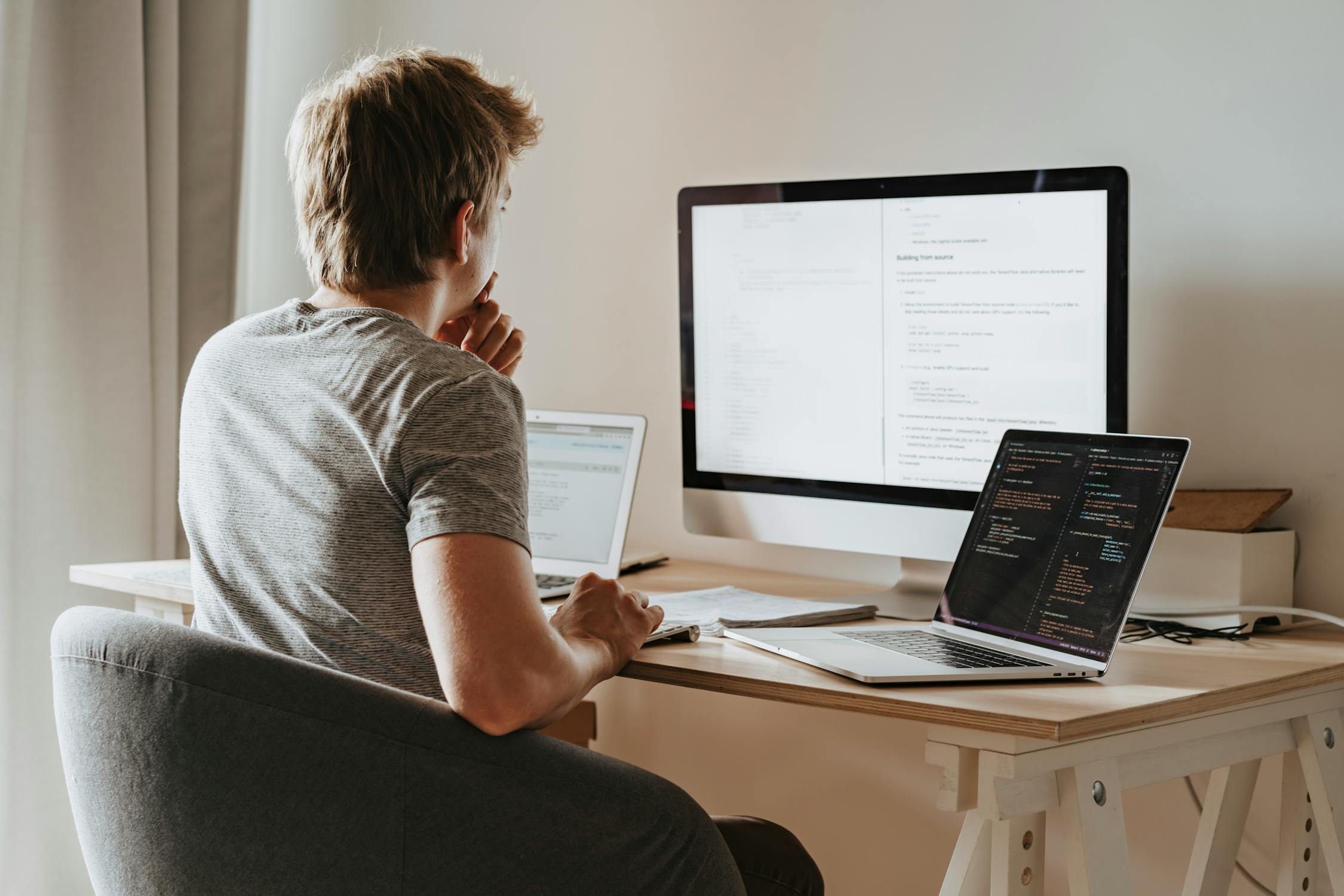 Man sitting in front of three computers