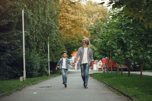 Free A grandfather and grandson enjoying a walk together in a lush green park. Stock Photo