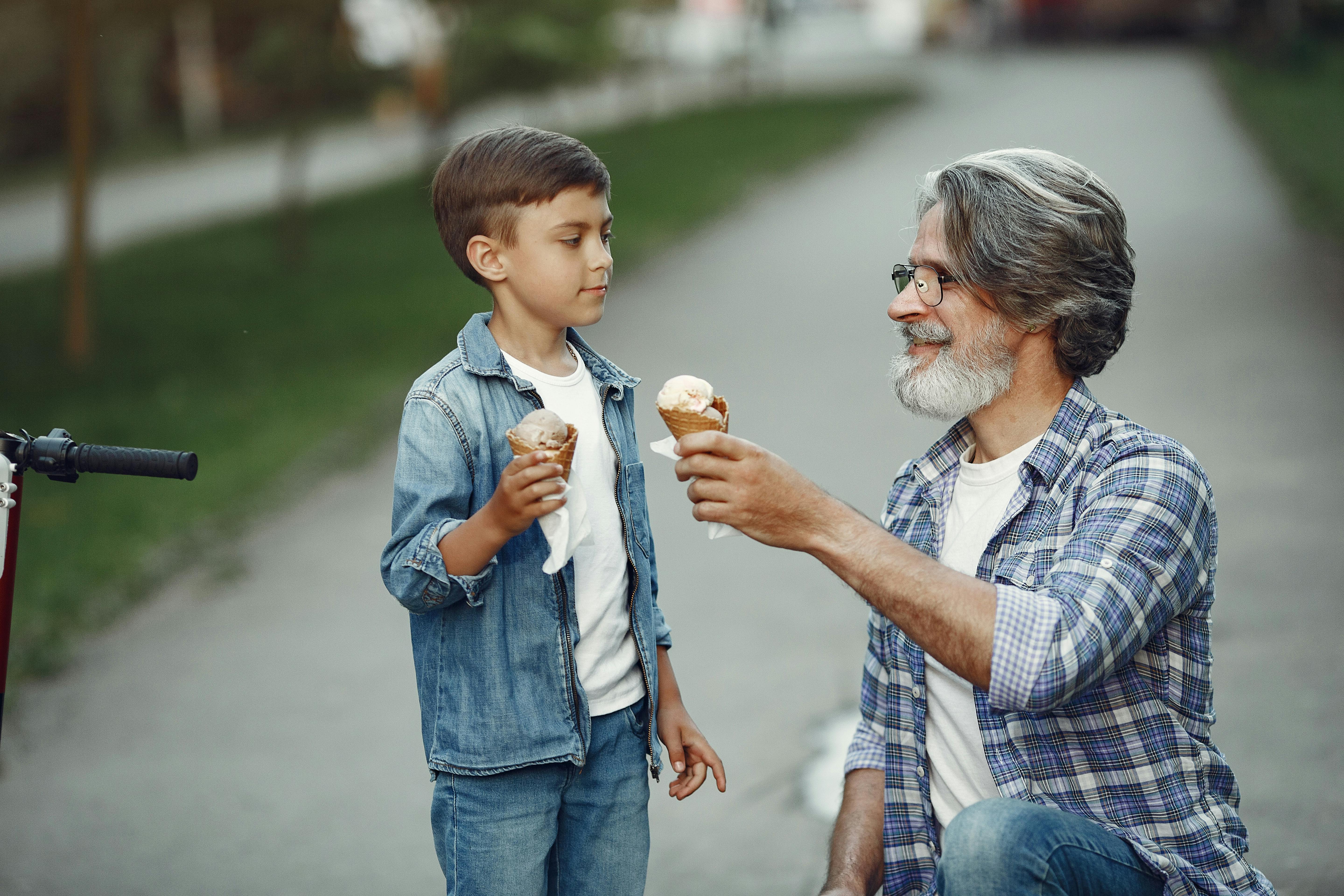 Grandfather and grandson sharing ice cream in a park. A heartwarming moment of bonding and togetherness.