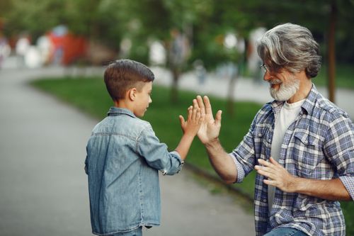Free Joyful moment of a grandfather and grandson playing high-five game in the park. Stock Photo