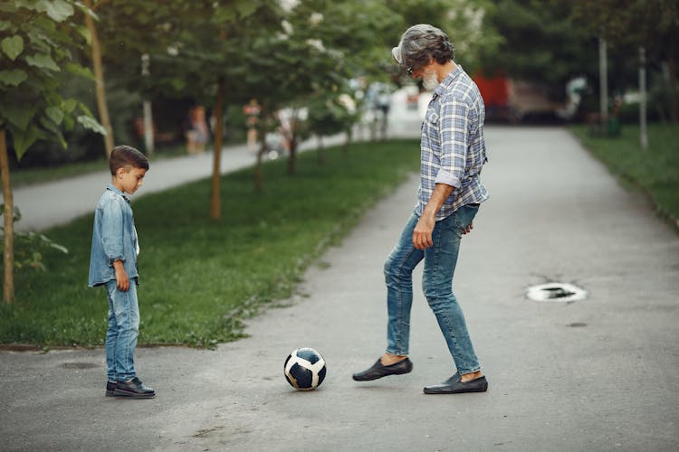 Bearded Man In Checked Shirt Playing Football With A Boy