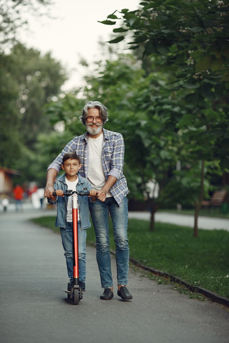 Happy Elderly Man With Boy Riding On Scooter