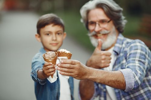 Free Capture of a grandfather and grandson sharing joyful moments with ice cream cones on a sunny day. Stock Photo