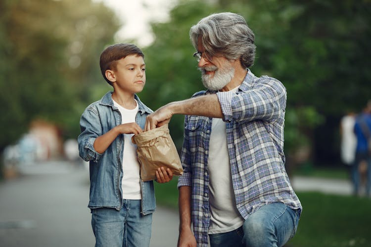 Man And Boy With Bag Of Snacks On City Street