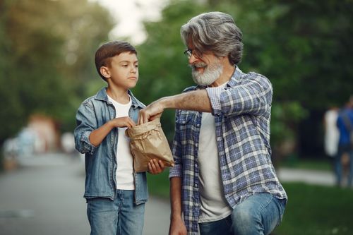 Free A senior man and young boy enjoy a snack together on a city street. Stock Photo