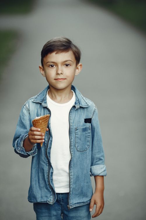 Free Young boy stands outdoors holding an empty ice cream cone, enjoying a summer day. Stock Photo