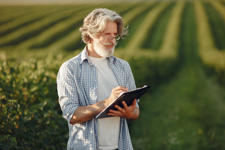 Elderly Man Noting While Standing On A Field 