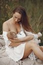 母亲在自然环境中宁静地母乳喂养婴儿，凸显了母子间的纽带与爱