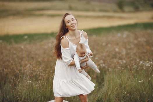 一位快乐的母亲和婴儿在花海中享受着阳光明媚的一天