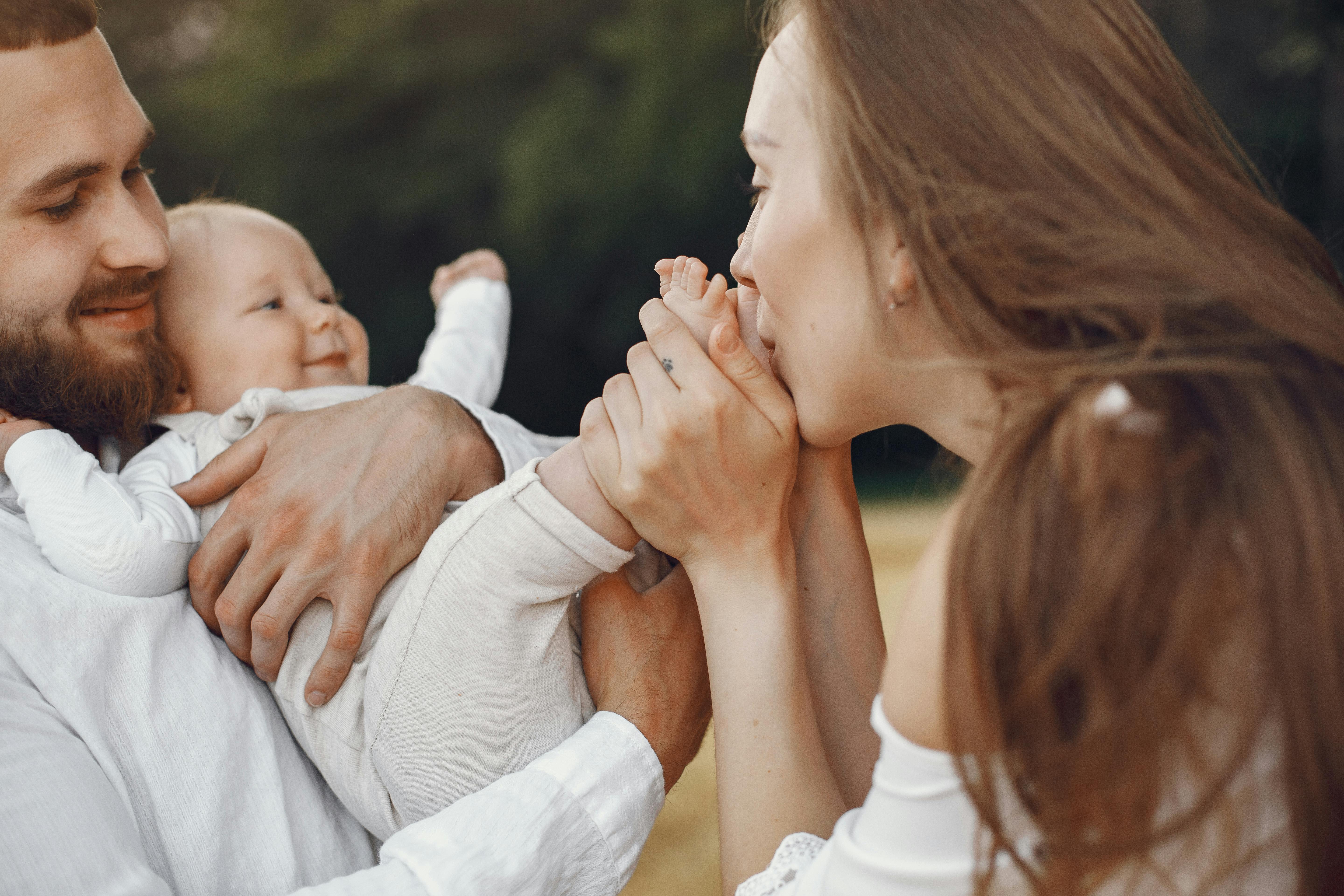 A joyful family scene of parents and their baby enjoying quality time outdoors, full of love and affection.