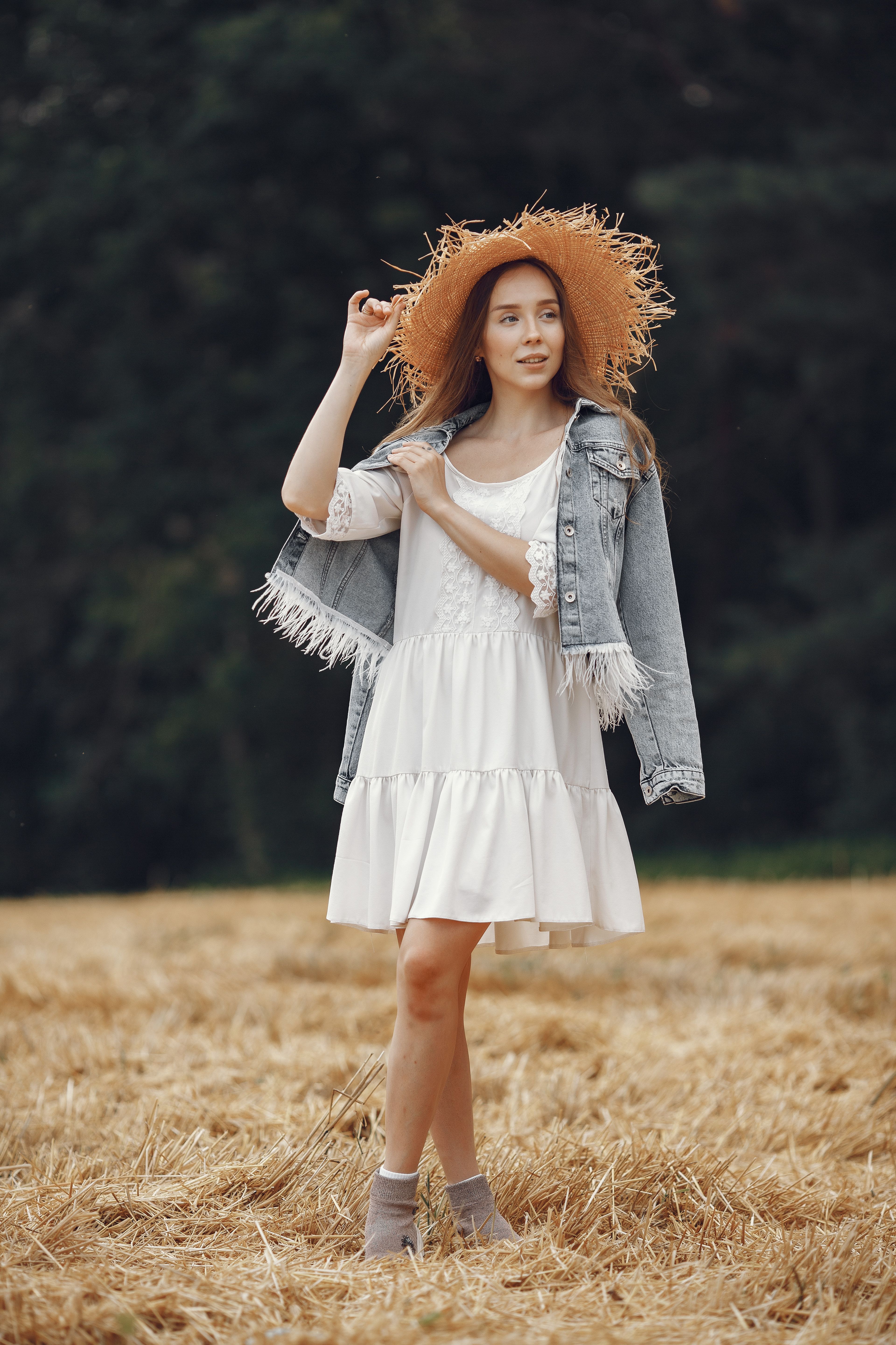 woman in white sundress with denim jacket over shoulders on a warm evening