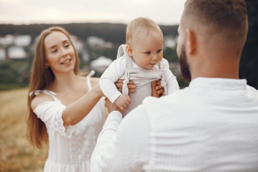 A happy family enjoying outdoor time with their baby in a scenic field.