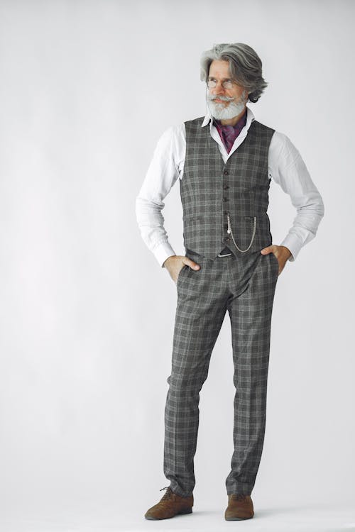 A Man in Checkered Vest and Pants Standing on the White Background