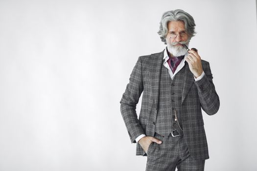 一位穿着定制西装、手持烟斗的杰出长者肖像，背景为白色