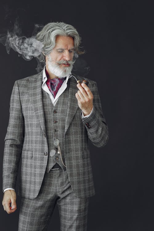Man in Black and Gray Plaid Suit Jacket Holding Black Tobacco Pipe