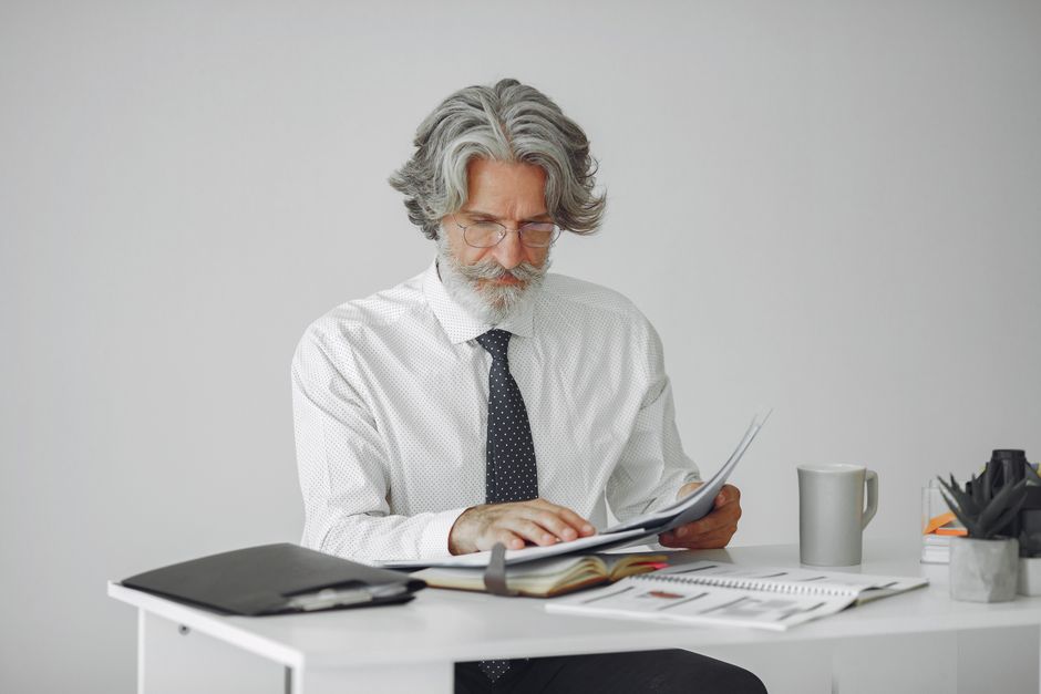 A worker in their 50s reviewing a retirement plan document and smiling A worker in their 50s reviewing a retirement plan document and smiling