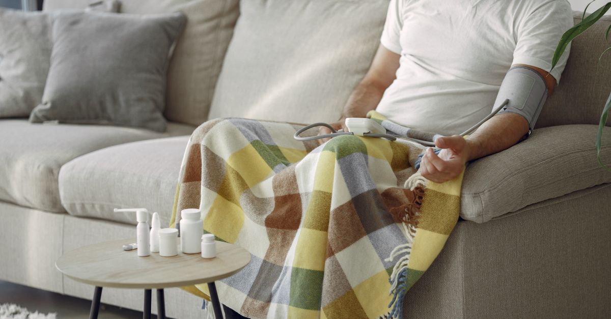 Elderly man monitoring blood pressure on a cozy couch at home, surrounded by medication. - Evidence evidence guide for citrus bergamot blood pressure meta-analysis