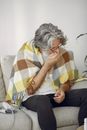 Woman in White and Yellow Plaid Scarf and Black Pants Sitting on White and Gray Couch