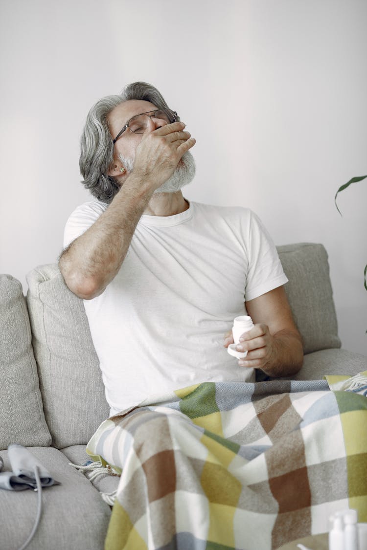 Man Sitting On The Couch Drinking His Medicine 