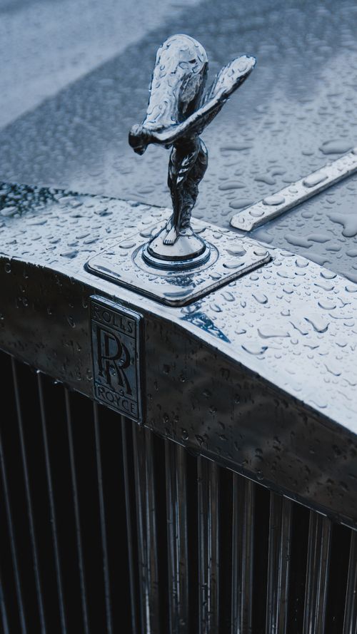 Free Close-up of a Rolls-Royce hood ornament with raindrops, showcasing luxury and detail. Stock Photo