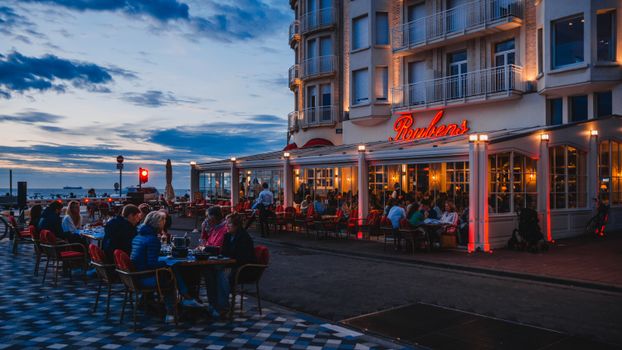 Outdoor dining scene at sunset in Knokke-Heist, Belgium, capturing vibrant seaside life.