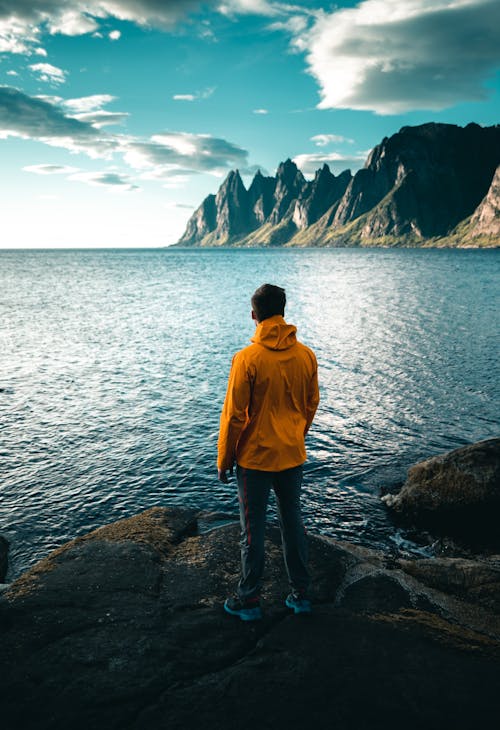 Hombre Con Sudadera Amarilla De Pie En Rocky Shore