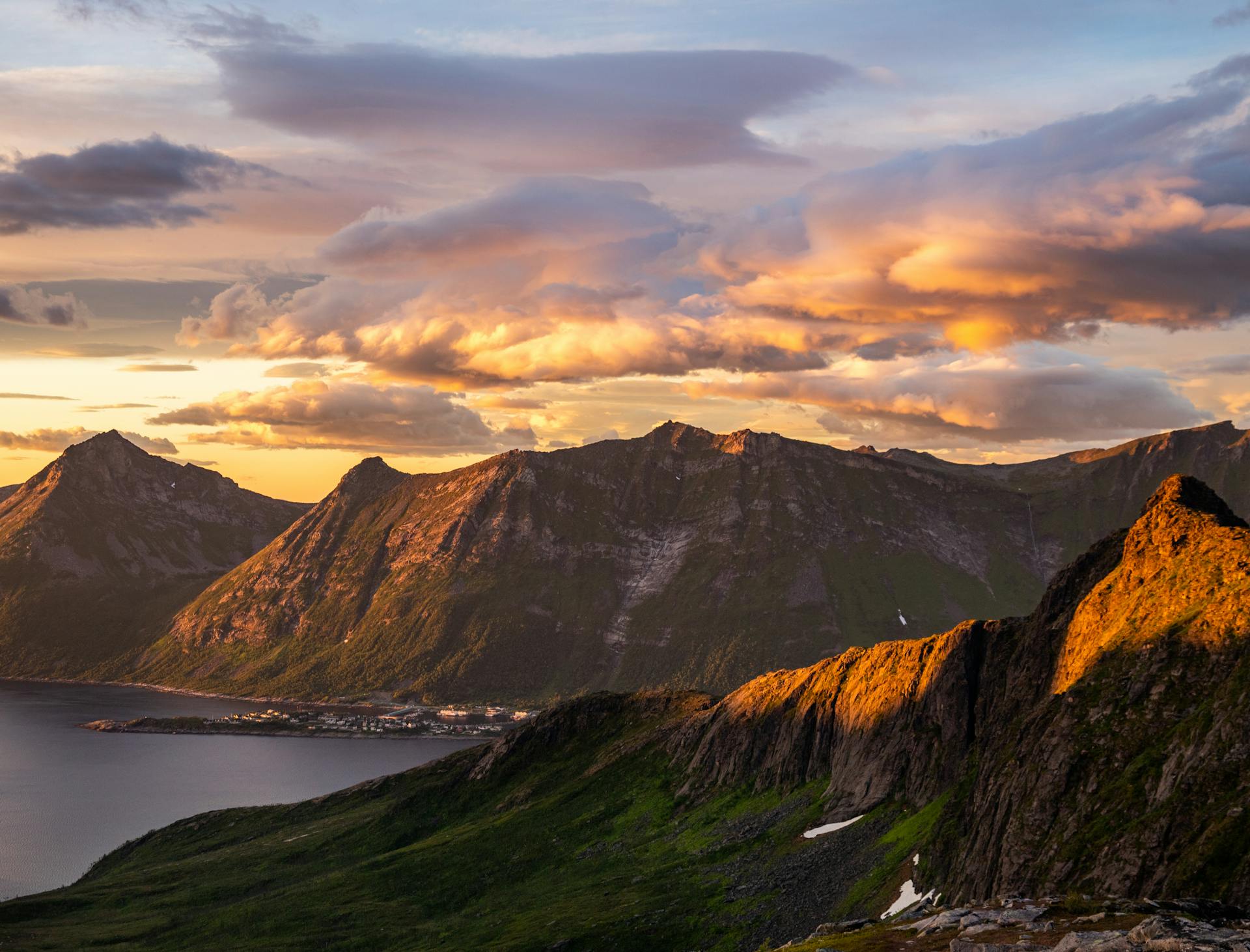 Breathtaking view of Troms og Finnmark mountains and ocean during a vibrant sunset.