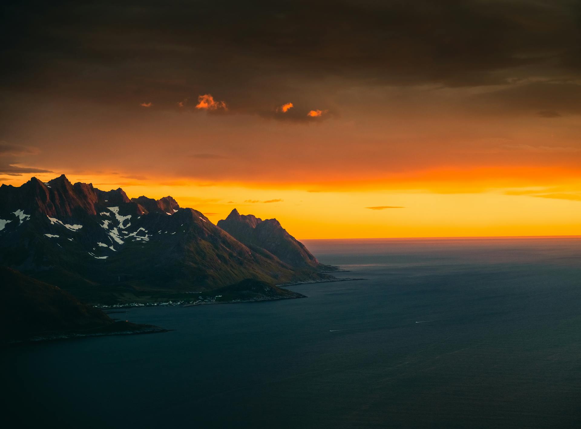 Stunning coastal view of Troms og Finnmark, Norway with a vivid sunset sky.