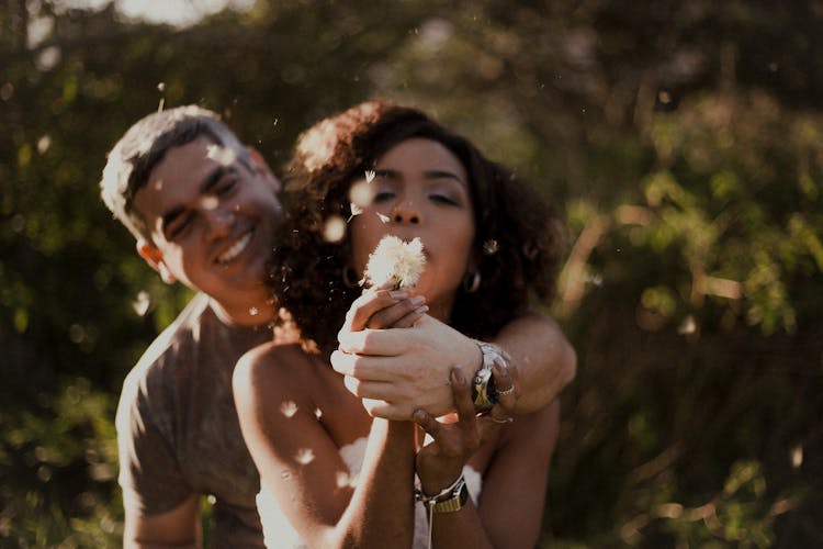 A Woman Blowing A Dandelion Flower