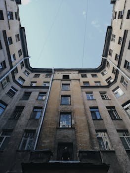 Low-angle shot of an urban residential building against a clear sky, showcasing architectural structure.