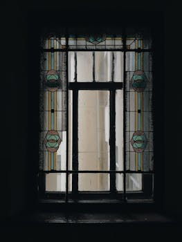 Elegant stained glass window with geometric Art Deco patterns casting soft light indoors.