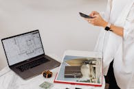 A Person Using a Cellphone near a Laptop