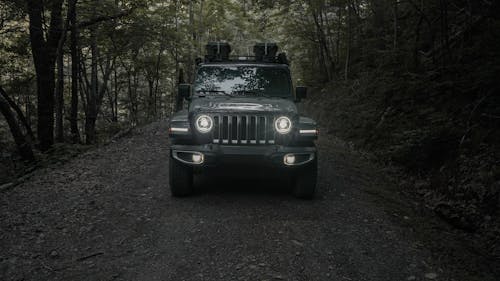 Vehicle with Illuminated Headlights on Dirt Road