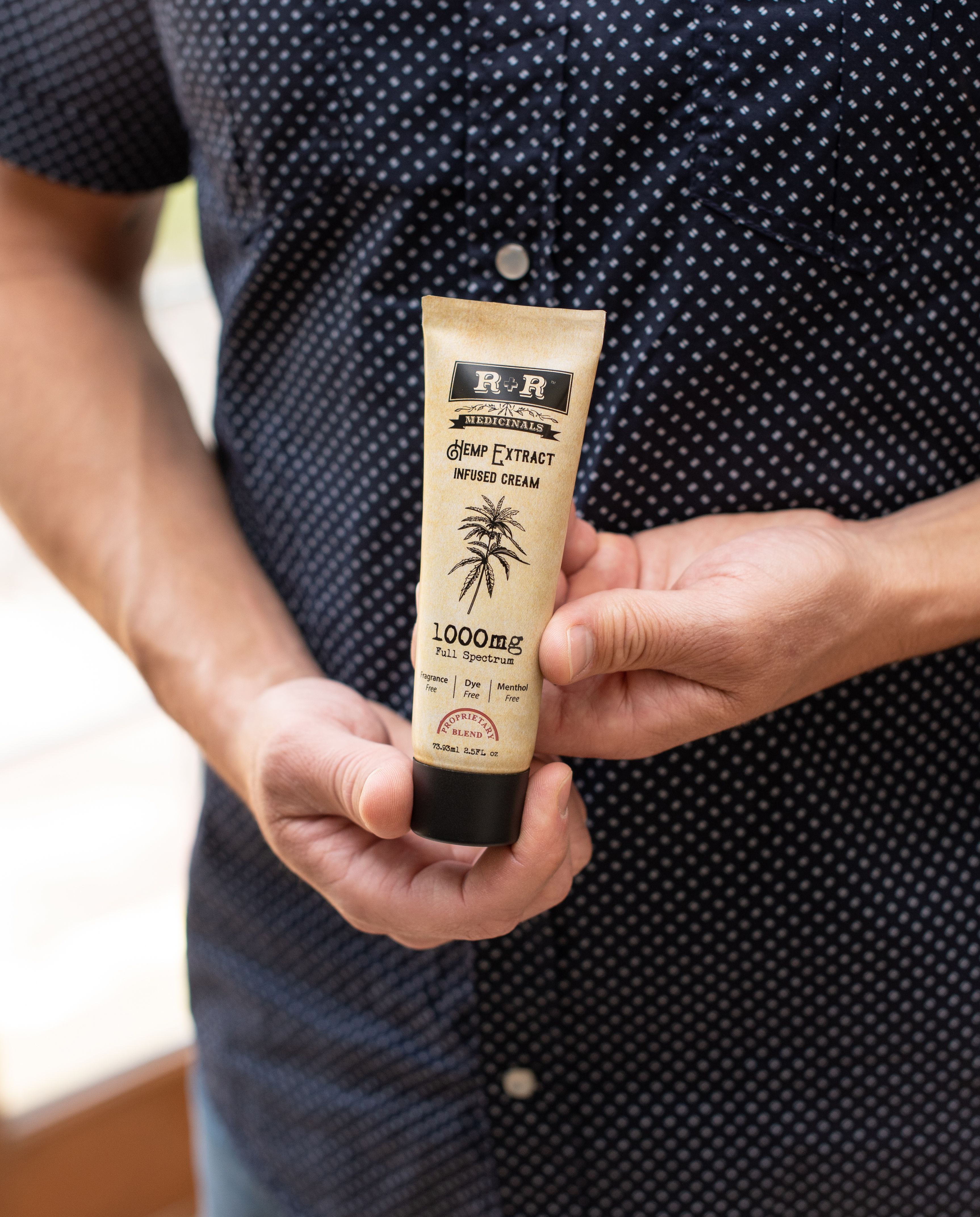 A person holding a hemp extract infused cream tube outdoors, showcasing 1000mg strength.