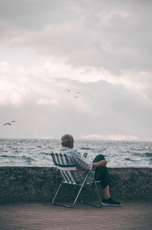 Man Sitting on a Chair Near Concrete Barrier