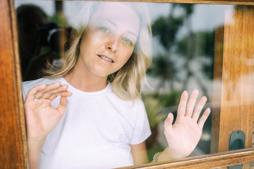 Free Woman in White Crew Neck T-shirt Behind Glass Window Stock Photo