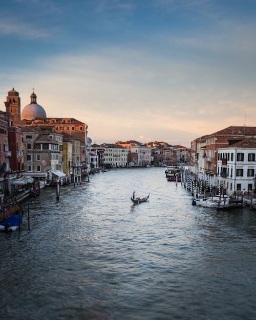 Person Standing on Floating Boat Between Houses