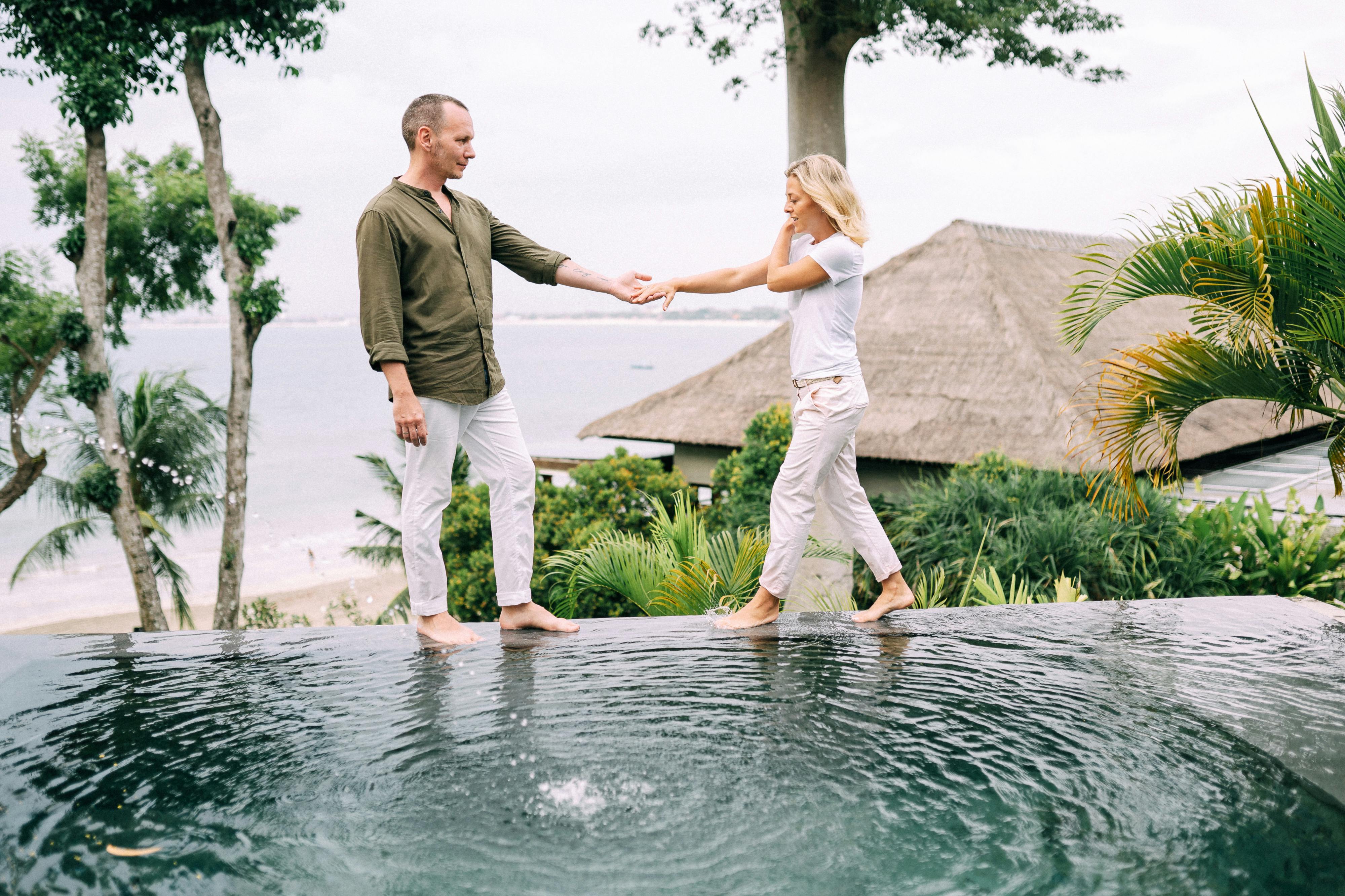 Couple holding hands and enjoying a tropical vacation by the poolside.