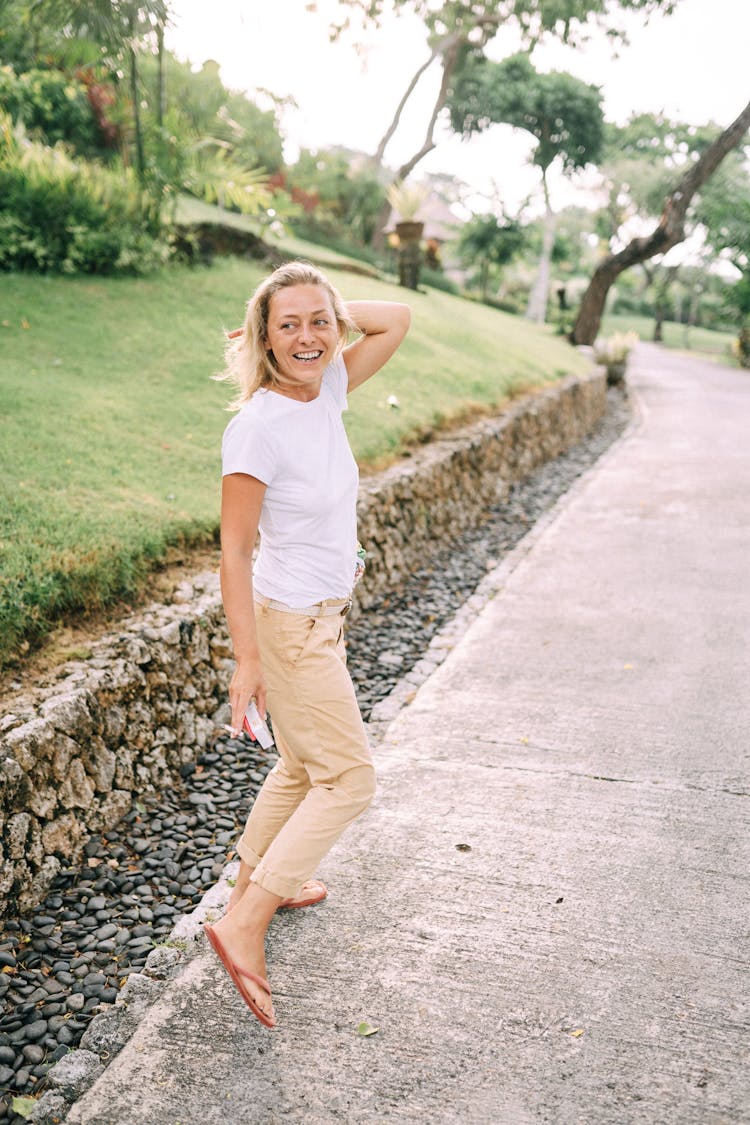 Woman In White T-shirt And Khaki Pants Standing On Gray Concrete Pathway