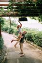 A Man Lifting a Woman on Concrete Pathway