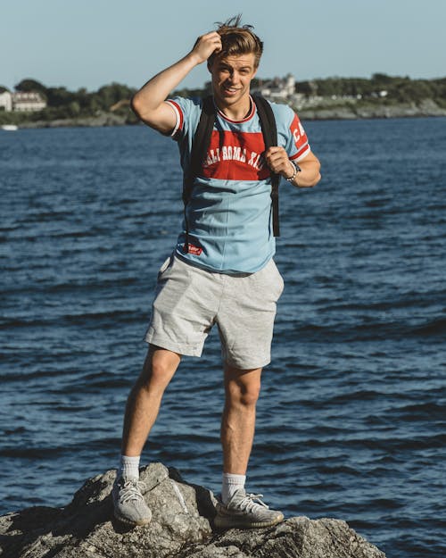 A Man with a Backpack Standing on a Rock 