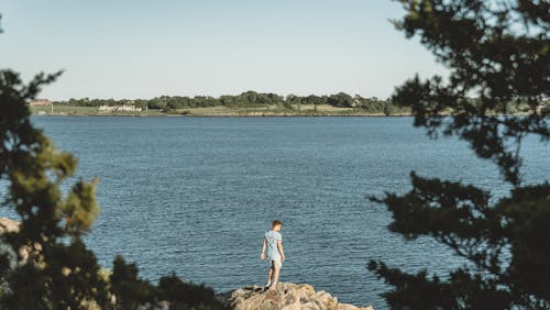 Free A Man Standing on Rocks Overlooking the Lake Stock Photo