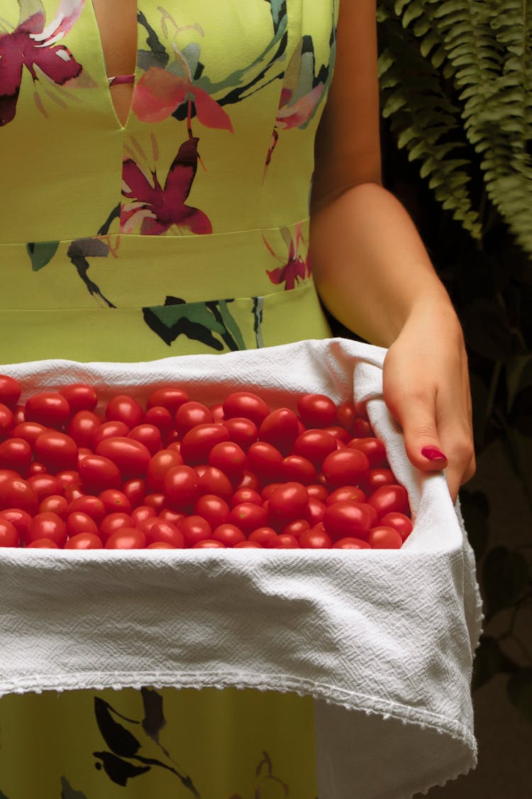 A Person Carrying A Box Of Red Tomatoes