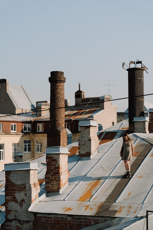 A woman standing on a roof with chimneys