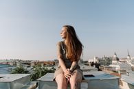 一名年轻女子纹着身，在屋顶上放松身心，欣赏阳光明媚的城市景观