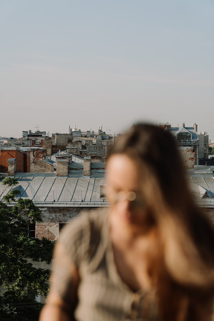 Woman In Brown Coat Standing On Top Of Building