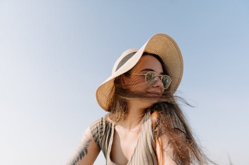 Free Woman in White and Black Stripe Tank Top Wearing Brown Sun Hat Stock Photo